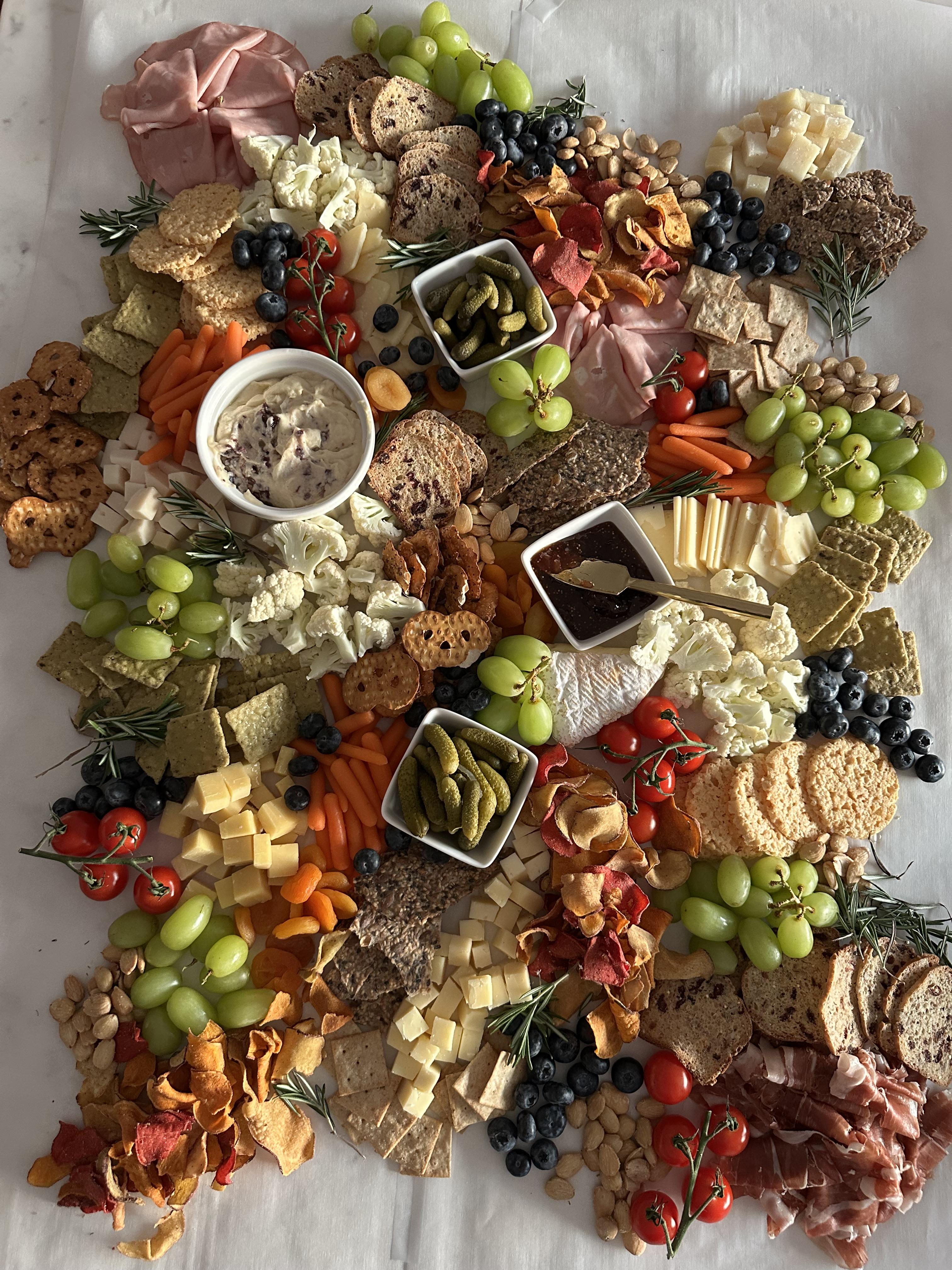 Large grazing table with abundant cheeses, fruits, dips, and crackers